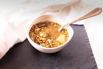 detail of a deep dish with lentils and vegetables with a spoon on the black board ready to eat