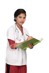 Young woman doctor with stethoscope is writing in book