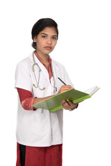 Young woman doctor with stethoscope is writing in book