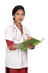 Young woman doctor with stethoscope is writing in book