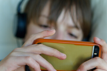 Caucasian teenage boy watching a video on a smartphone wearing earphones