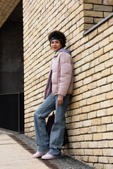 African american woman looking at camera near building on street