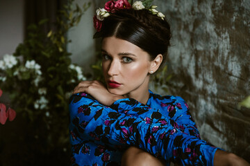 Fototapeta premium Portrait of beautiful young woman with red lips and hairdo with flowers