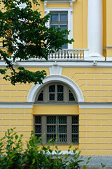Arched window and a rectangular window with a balcony and white columns against a yellow wall. From a series of windows of St. Petersburg..