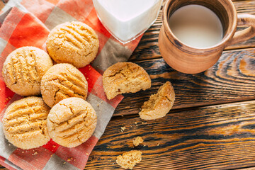 Peanut butter cookies and clay mug with milk on wooden background