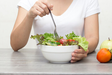 Asian women on white shirt eating vegetable mix salad on table for healthy and diet concept