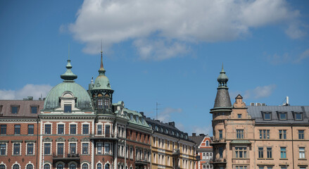 Fototapeta na wymiar Roofs and fronts of old 1800s stone buildings in Stockholm at the bay Ladugårdsviken 