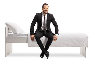 Full length shot of a businessman in a suit and tie sitting on a bed