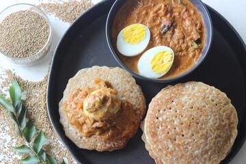 Kodo millet pancakes served with egg roast. Pancake is made with a fermented batter of kodo millet, flattened rice, coconut. Egg roast is Boiled egg in a spicy gravy of onions, tomatoes, spices