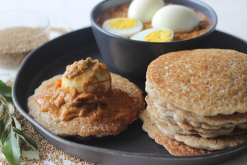 Kodo millet pancakes served with egg roast. Pancake is made with a fermented batter of kodo millet, flattened rice, coconut. Egg roast is Boiled egg in a spicy gravy of onions, tomatoes, spices