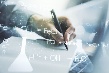 Double exposure of creative chemistry concept with hand writing in notebook on background with laptop, research and development concept