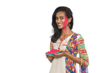 Beautiful young girl holding powdered color in plate on the occasion of Holi festival.