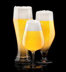 Set of fresh light beer glasses with bubble froth isolated on black background.