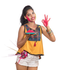 Beautiful young girl holding powdered color in plate with carnival mask on the occasion of Holi festival.