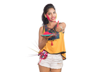 Beautiful young girl holding powdered color in plate with carnival mask on the occasion of Holi festival.