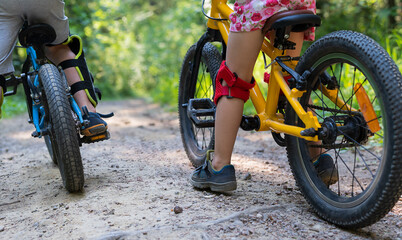 Children on a bicycles on an road in the forest. Summertime.