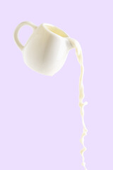 pouring milk from milk jug isolated on purple background