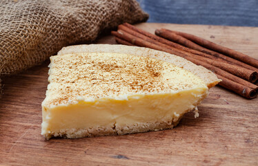 traditional South African milk tart on rustic farm style table with burlap and cinnamon coils