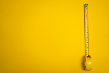 yellow measuring tape viewed from above on yellow background