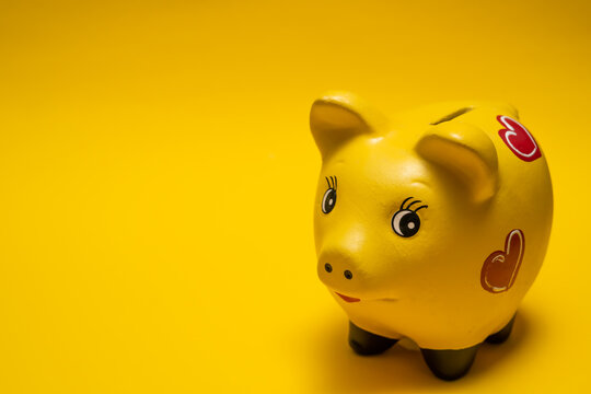 Yellow Piggy Bank With Red Hearts Paint On Yellow Infinite Background. For Presentations On Finance For Children Or Adults. Copy Space