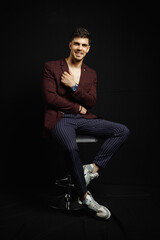 Portrait of an casual man sitting on the chair, Stylish businessman, Portrait of the beautiful posing in a Studio, Black background, Stylish man