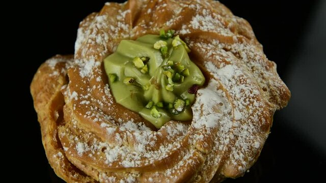Close up delicious italian desserts with pistachio cream called zeppole of St. Joseph on black background, top view, zoom in. Zeppole is an apulian traditional pastries for celebration of Fathers day
