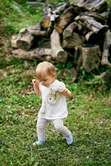 Kid walks in the green meadow against the background of stumps