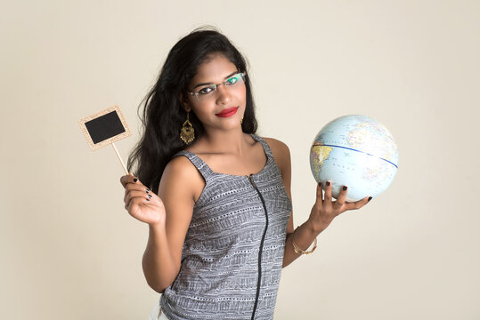 Portrait of young Girl holding and posing with a world globe and small black board