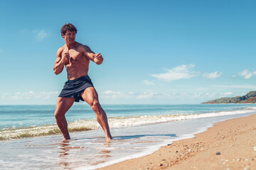 Fototapeta na wymiar A muay thai or kickboxer training with shadow boxing outdoor at seashore
