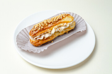 Eclair with cream and strawberries. On a white plate High quality photo