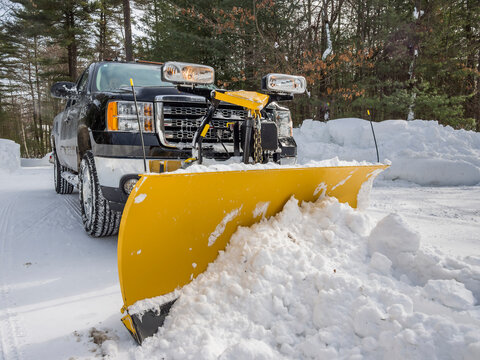 Pickup truck plowing snow off driveway