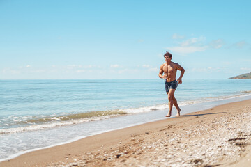 Young muscular guy, with a bare torso running along the beach