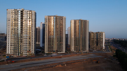 Construction of a new city block. New construction of modern multi-storey buildings. The setting sun is reflected in the windows of the houses. Aerial photography.