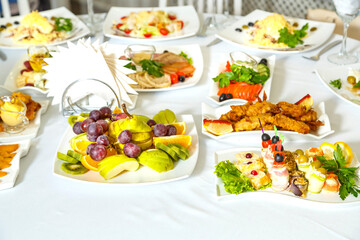 banquet table with white tablecloth with snacks and fruits and champagne.