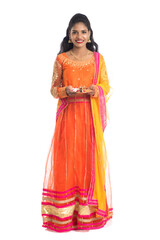 Beautiful Indian young girl holding pooja thali or performing worship on a white background