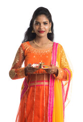 Beautiful Indian young girl holding pooja thali or performing worship on a white background