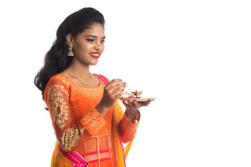 Beautiful Indian young girl holding pooja thali or performing worship on a white background