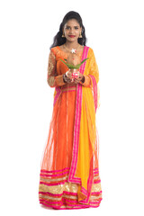 Indian Woman holding a traditional copper kalash, Indian Festival, copper kalash with coconut and mango leaf with floral decoration, essential in hindu puja.