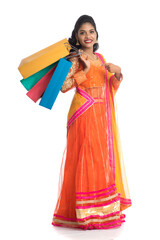 Beautiful Indian young girl holding shopping bags while wearing traditional ethnic wear. Isolated on a white background