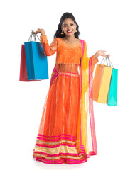 Beautiful Indian young girl holding shopping bags while wearing traditional ethnic wear. Isolated on a white background