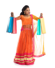 Beautiful Indian young girl holding shopping bags while wearing traditional ethnic wear. Isolated on a white background