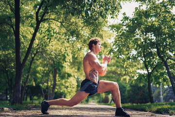 young fitness man runner stretching legs before run