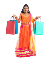 Beautiful Indian young girl holding shopping bags while wearing traditional ethnic wear. Isolated on a white background