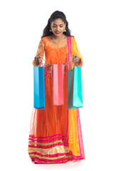 Beautiful Indian young girl holding shopping bags while wearing traditional ethnic wear. Isolated on a white background