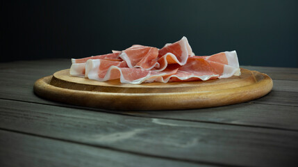 Italian prosciutto crudo, wooden plate of raw ham, cold cuts still life