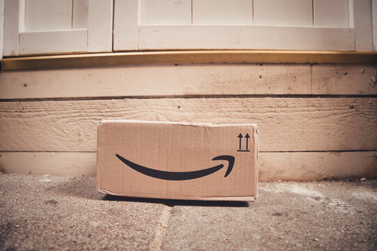 An Amazon Prime Parcel Delivery Cardboard Box Left In Front Of Wooden Door 