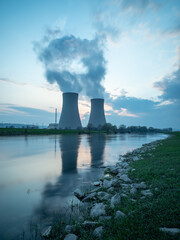 Nuclear power plant against sky by the river at sunset