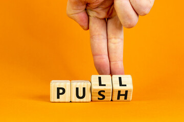Pull or push symbol. Businessman turns wooden cubes and changes the word 'push' to 'pull'. Beautiful orange background, copy space. Business and pull or push concept. - obrazy, fototapety, plakaty
