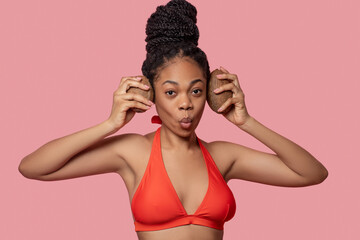 Fototapeta premium Dark-skinned woman holding coconuts and looking enjoyed