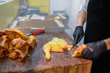 Butcher prep cuts chicken on wooden cutting board. Fresh and healthy food preparation concept
